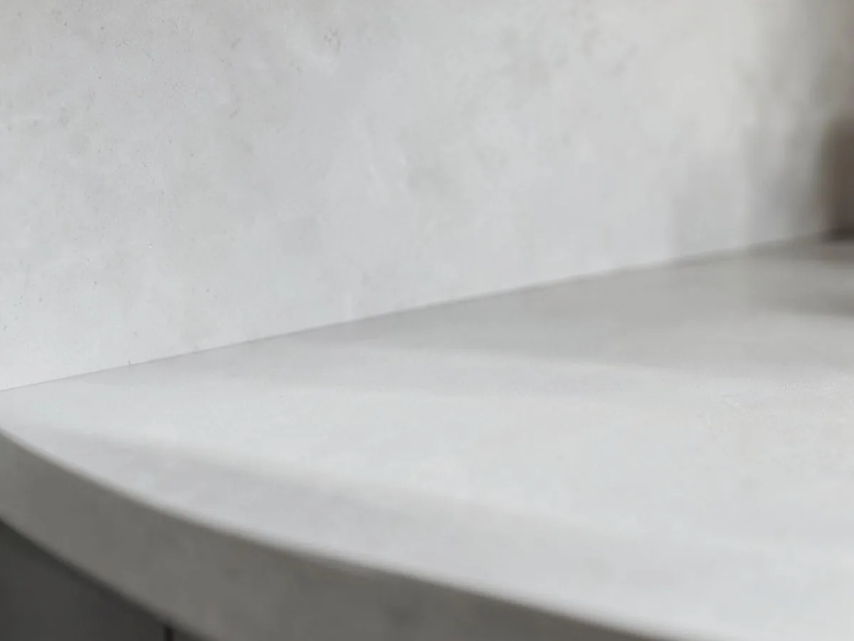 Smooth pale grey microcement wall finish in soft daylight