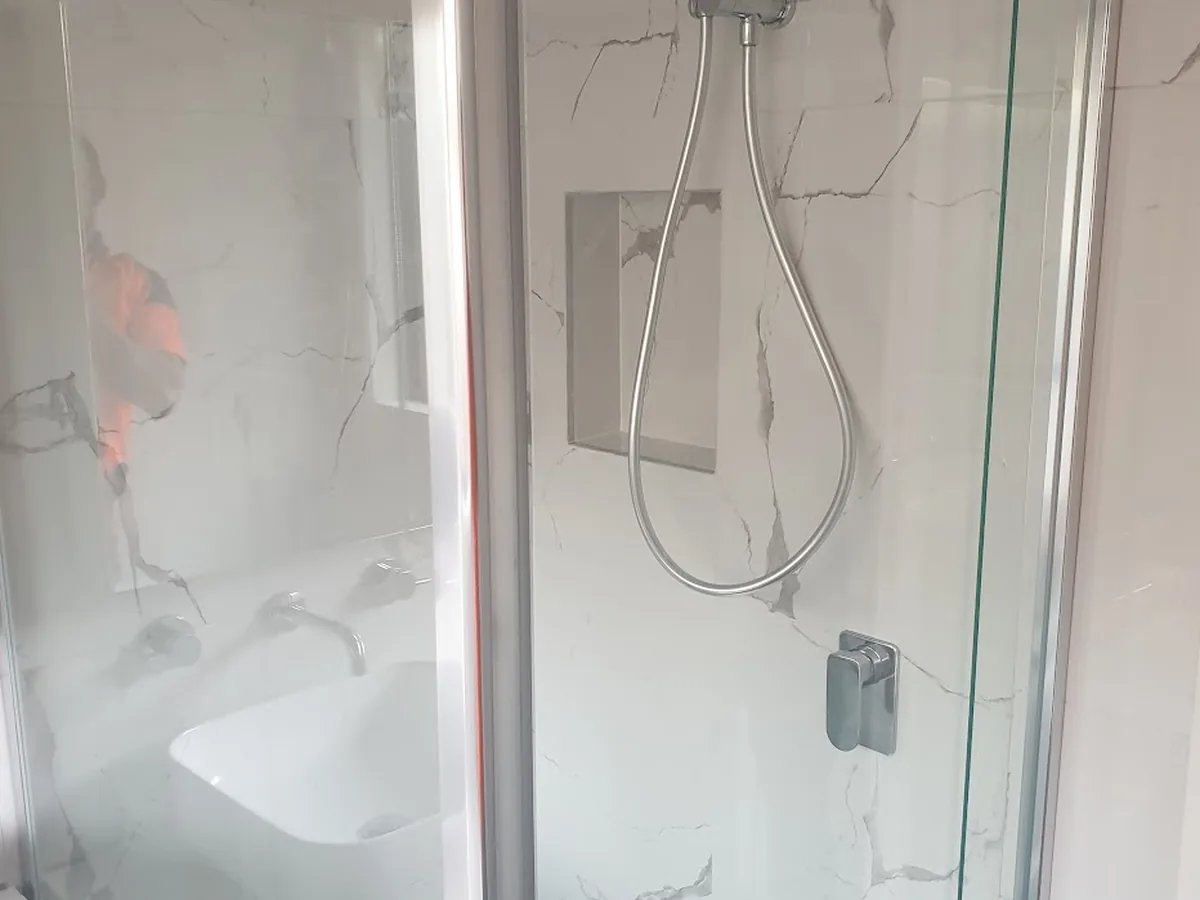 Shower detail from a completed Bendigo bathroom renovation — chrome shower head, wall niche and glass screen