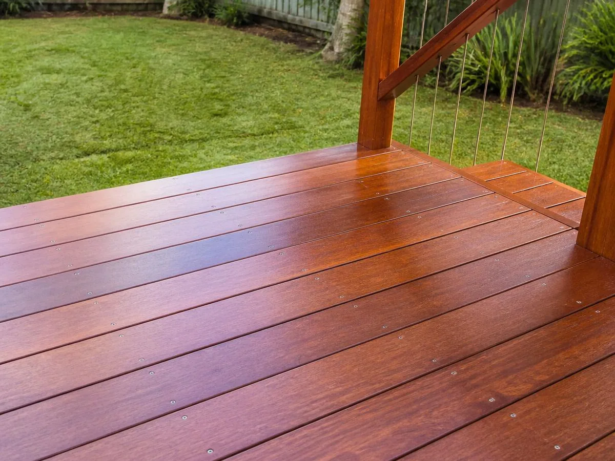Close view of freshly oiled hardwood deck boards with even gapping, screw fixings and timber handrail