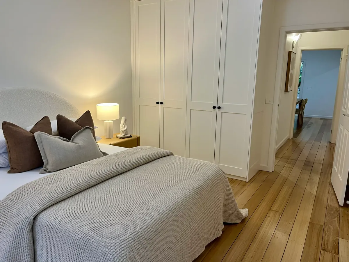 Renovated bedroom with timber floors, built-in wardrobes and warm styling — BMR home renovation finishing work